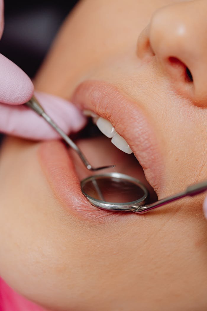 Close-up view of a patient's dental check-up using dental mirror and tools.